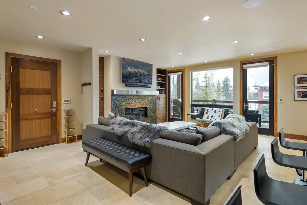A cozy living area with a plush sofa facing a natural gas fireplace, a large TV, and expansive windows that frame sunset views. Decorative items complete the atmosphere, making it ideal for relaxed evenings and social gatherings.