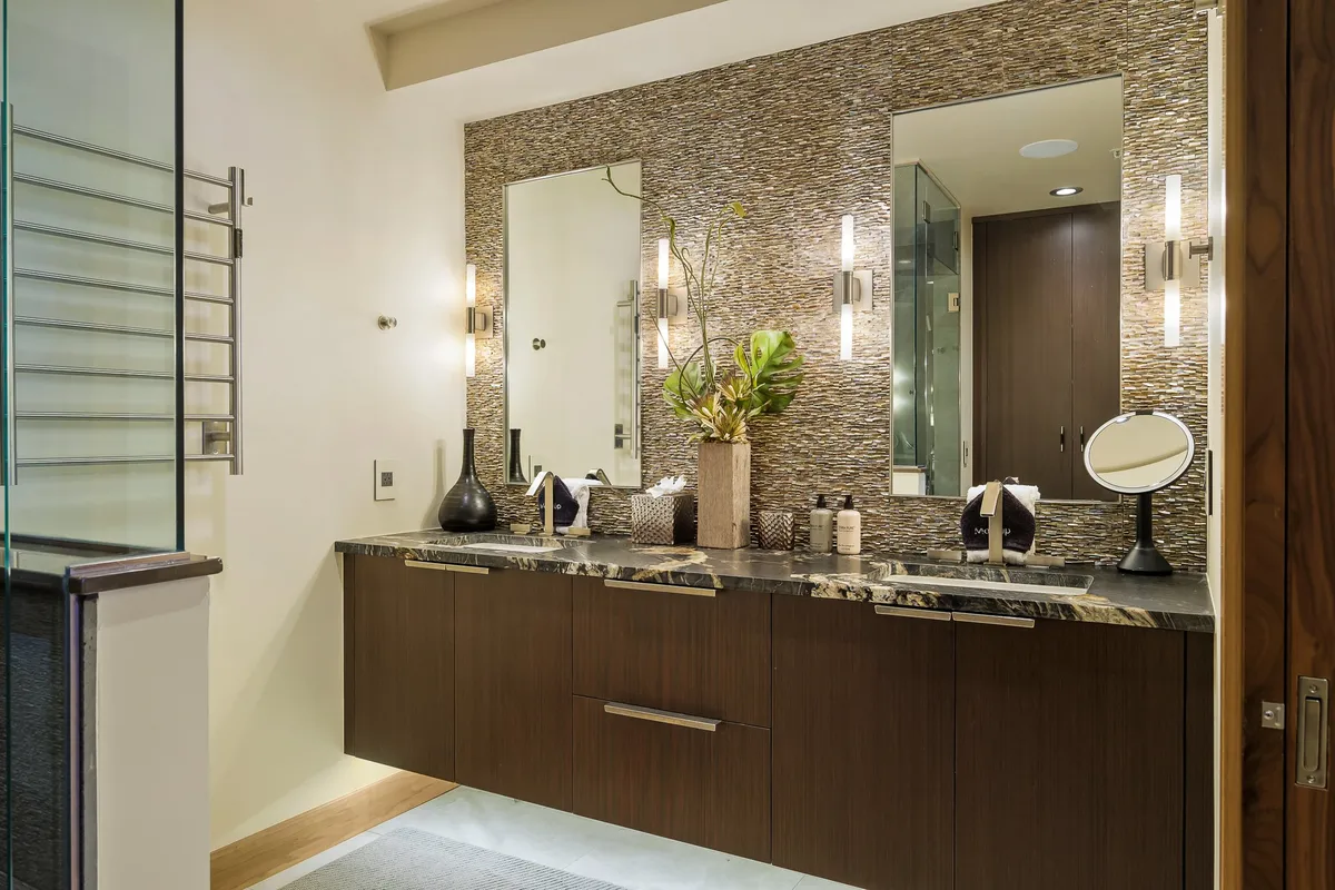 An elegant double sink vanity with stylish mirrors, soft lighting, and a decorative plant, evoking a spa-inspired atmosphere. The modern fixtures and spacious layout create a calming environment for self-care routines.